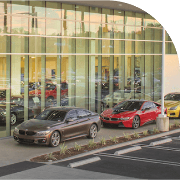 Cars parked in rows next to glass wall.